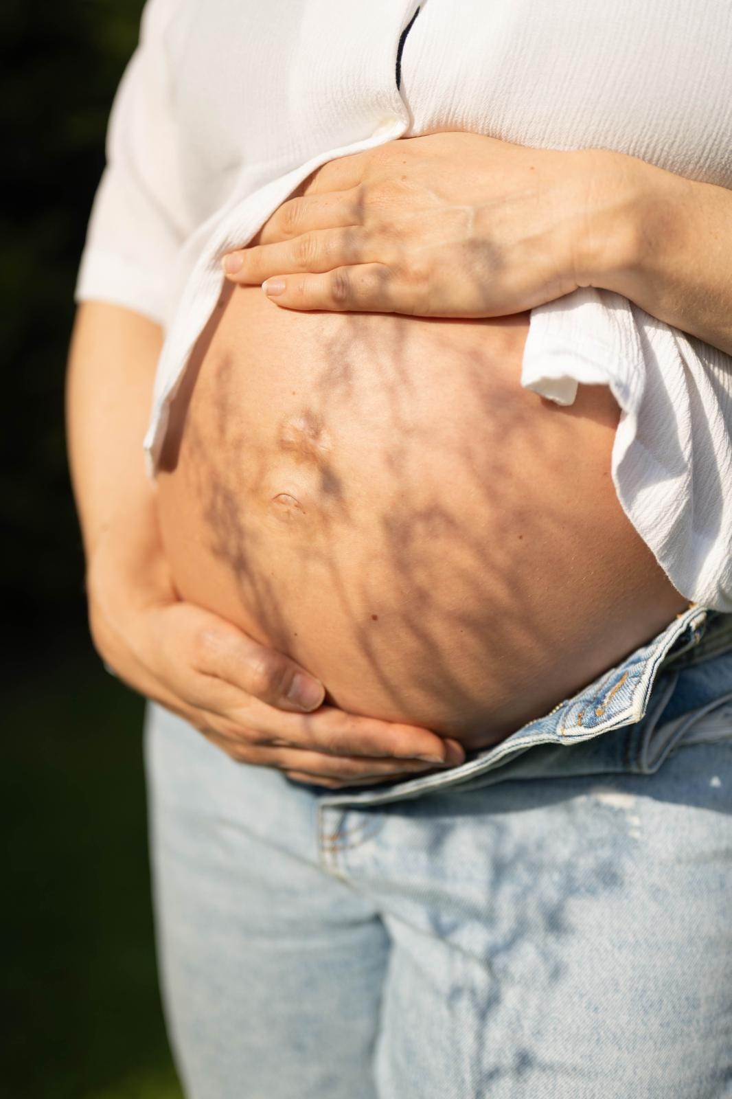 Babybauch mit Schattenspiel im Abendlicht